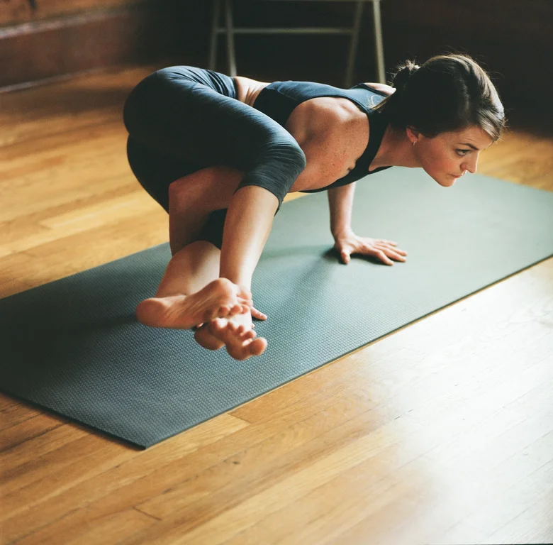 Student in an arm balance on a mat