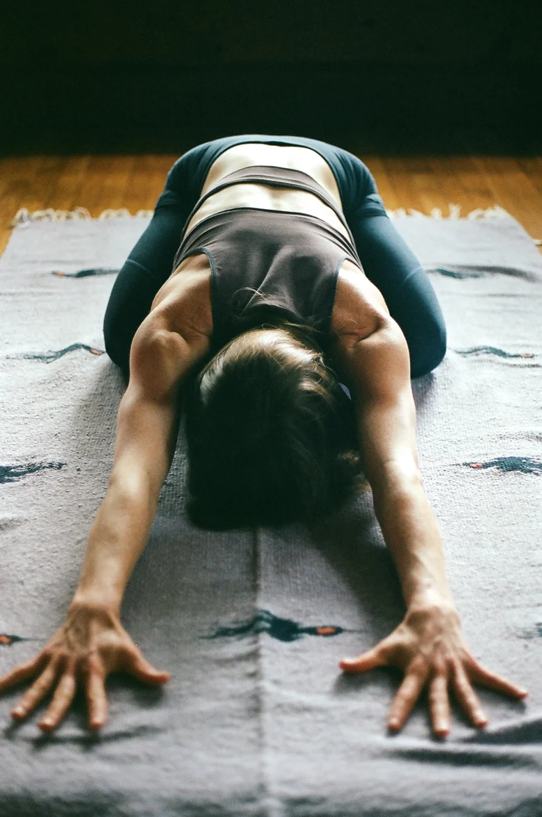 Student in child's pose on a woven rug