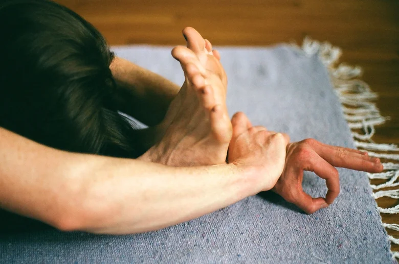 Hand resting in a mudra on a woven rug