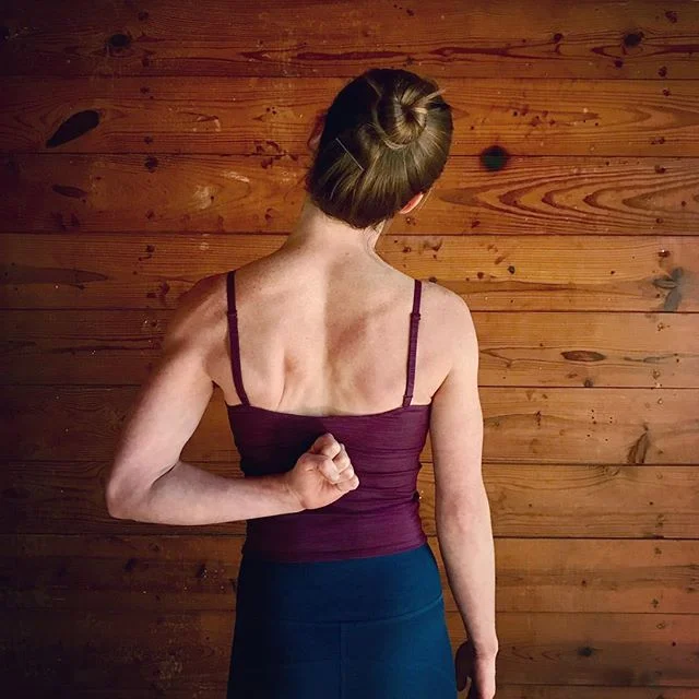 Gomukasana arm variation with a fist pressed into the back