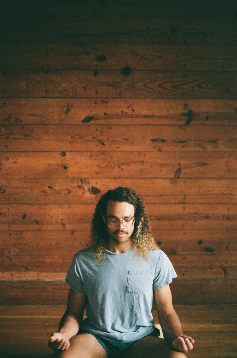 Student in seated meditation against a wood-paneled wall