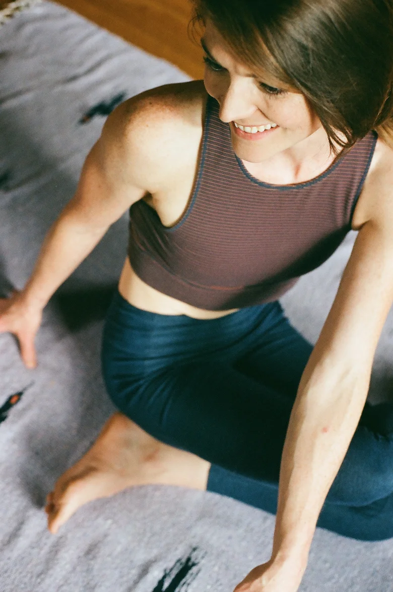 Student in a seated pose on a woven rug