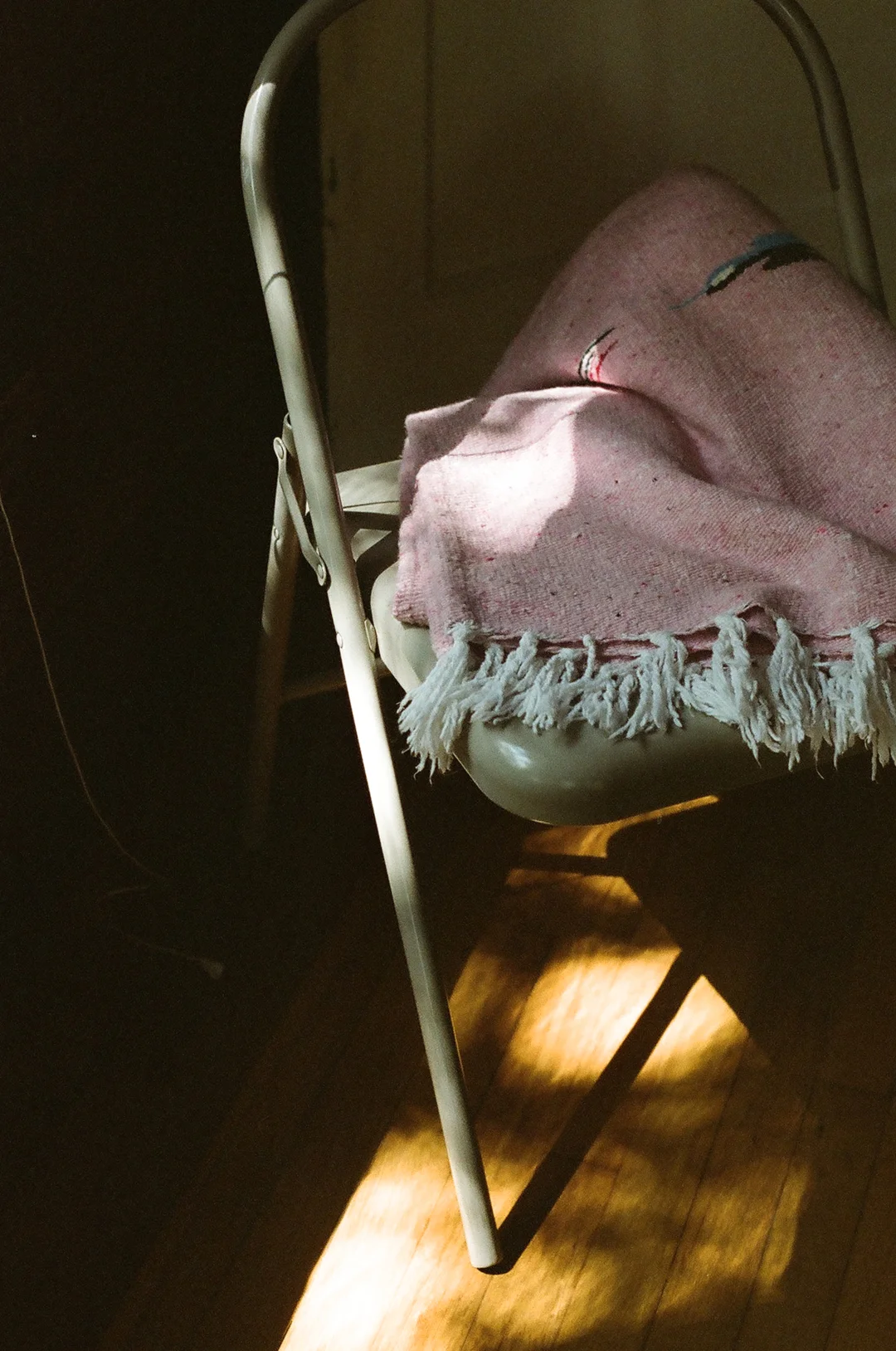 Folding chair with a pink blanket in afternoon light