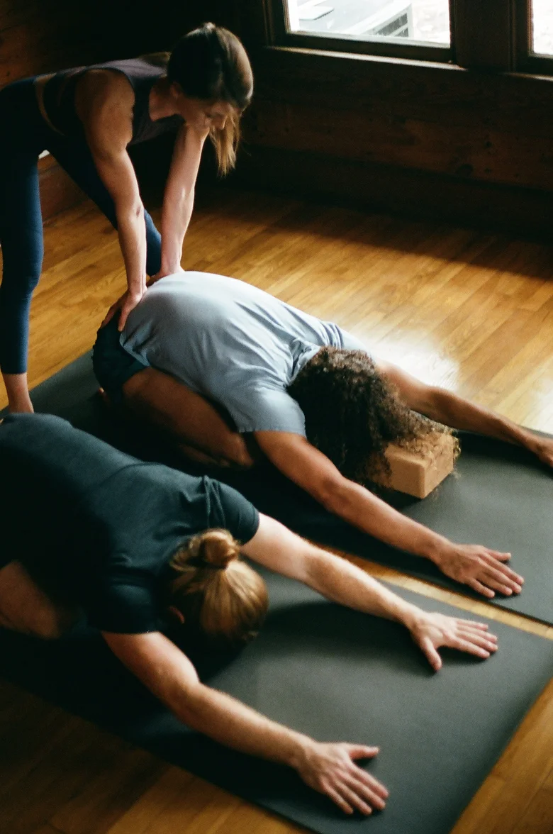 Teacher adjusting two students in child's pose