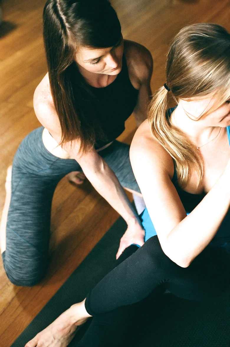 Teacher guiding a seated student on the studio floor